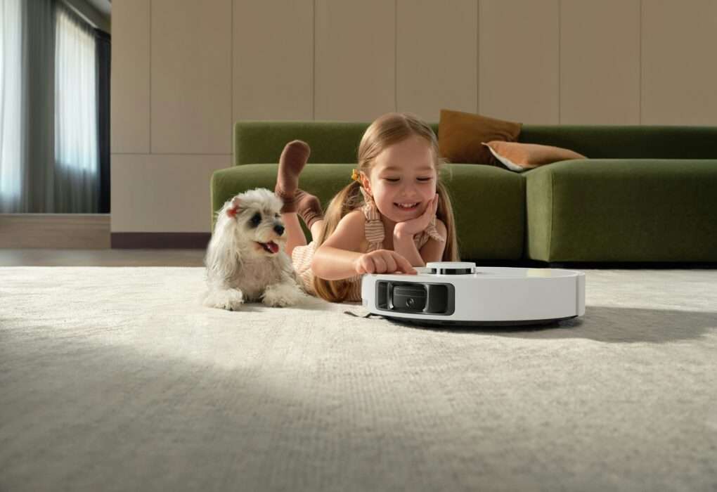 Autonomous robot vacuum cleaner cleaning carpet in modern living room with child and pet dog